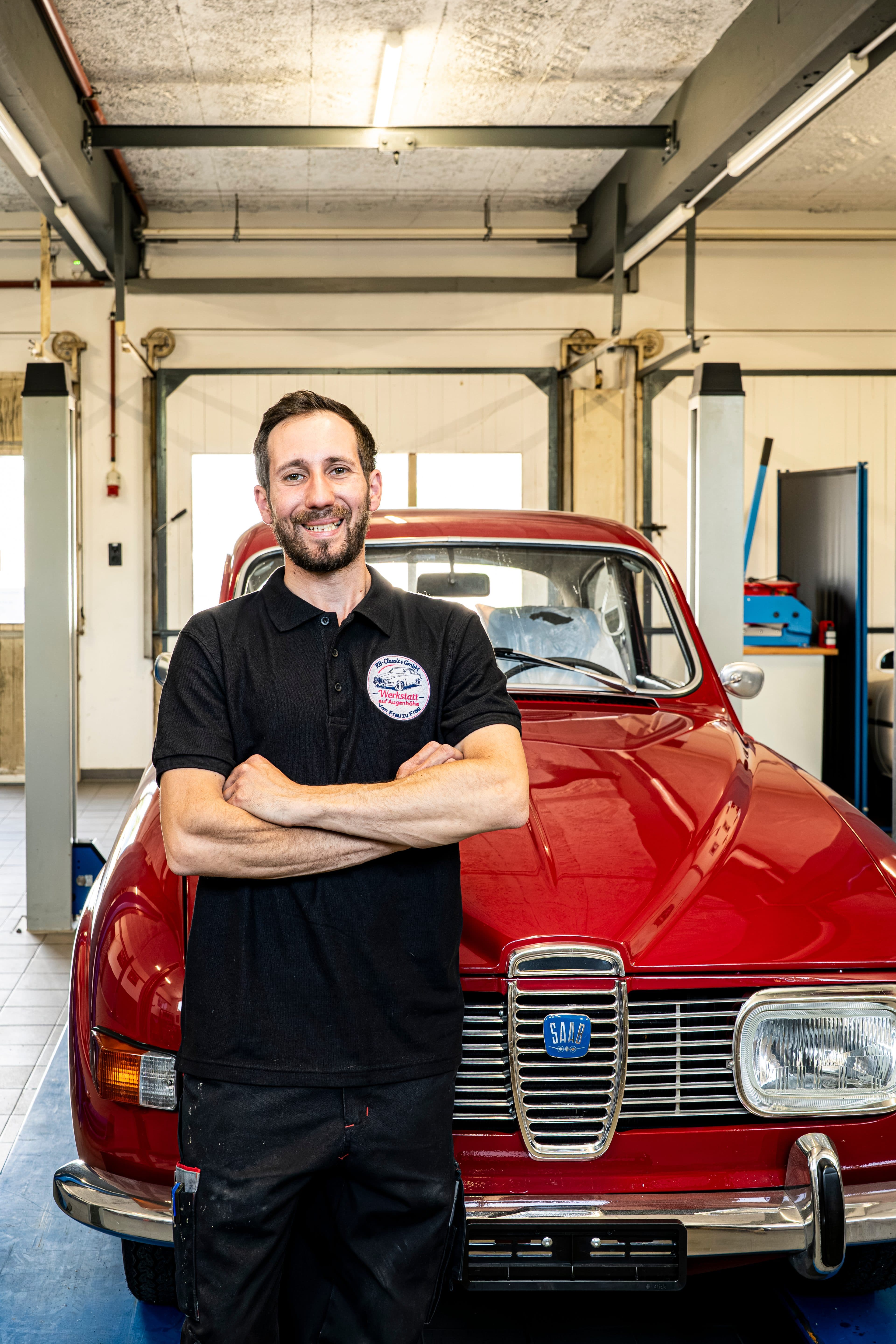 Ronny vor einem klassischen roten SAAB in der Werkstatt