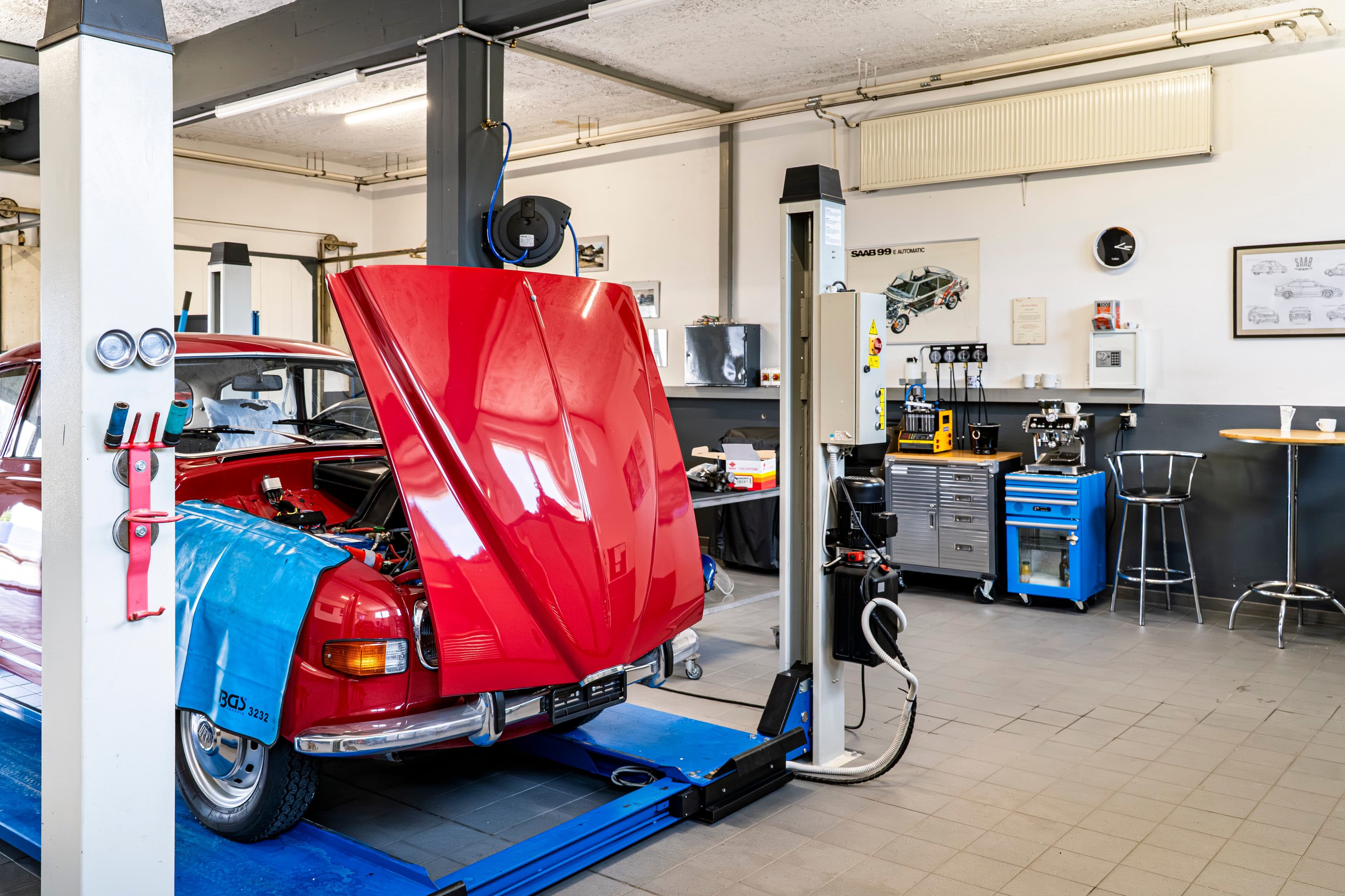 Klassischer roter SAAB mit geöffneter Motorhaube auf der Hebebühne